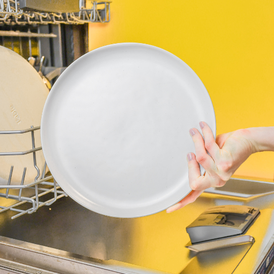 How to use dishwasher tablets 3: Hand is holding a sparkly clean dish in front of the dishwasher