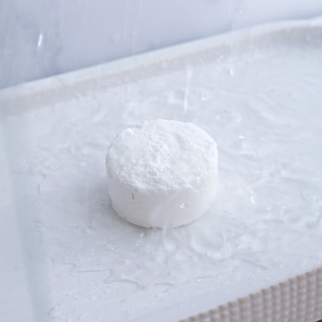 small natural ingredients shower steamer how to use image shows the shower bath bomb on white shower tile floor being splashed with water