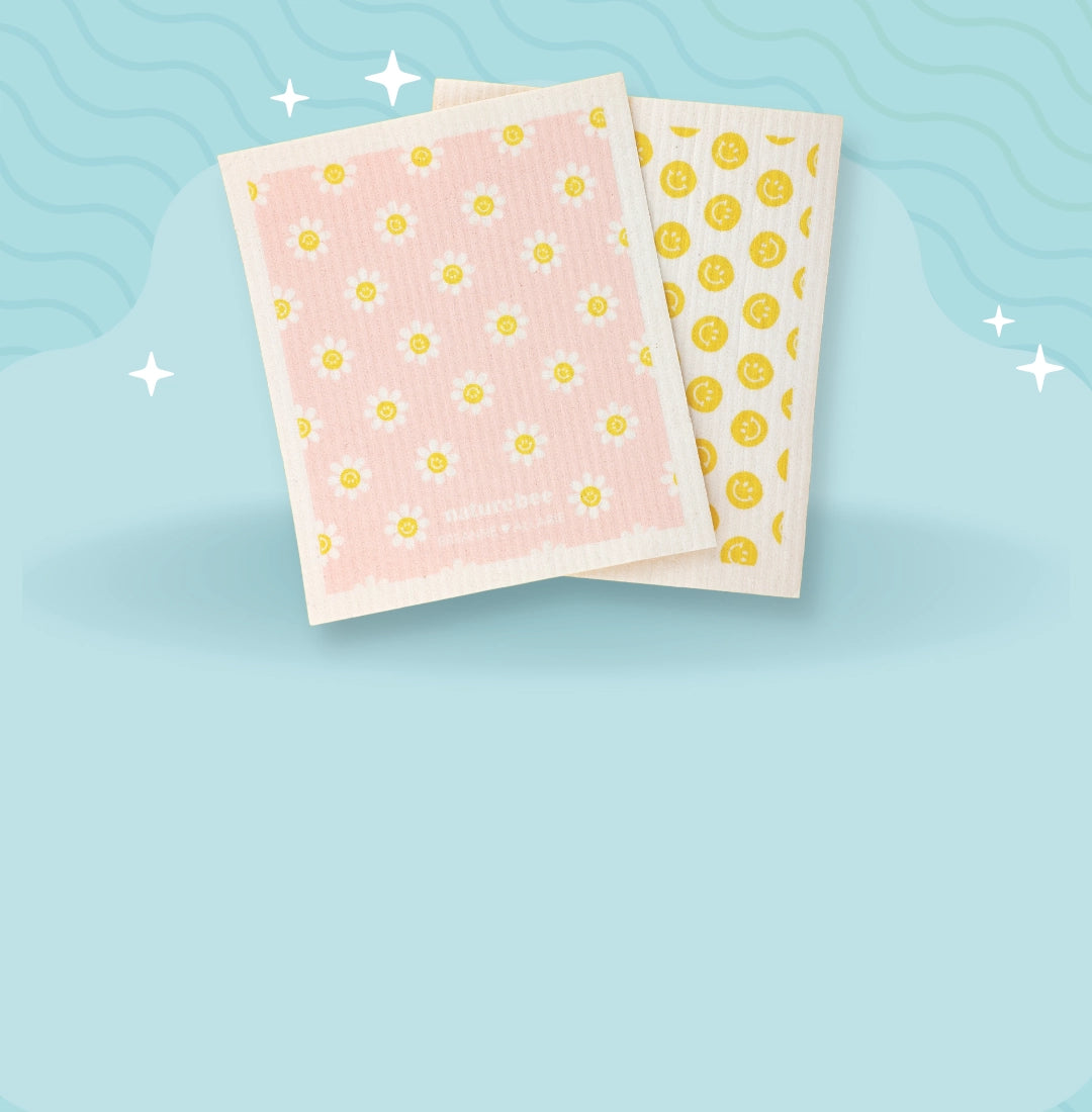 Light blue background with sparkles and squiggles. Kitchen dishcloths that are customizable and you can put your own design on them. One Swedish dishcloth is pink with flowers and the other has yellow smiley faces on it.