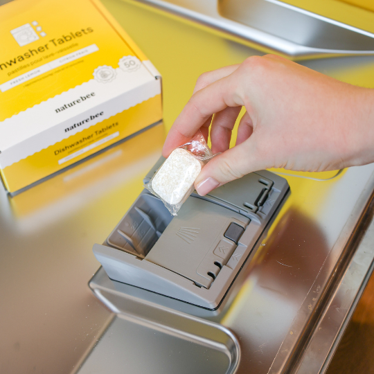 how to use dishwasher tablets image 2: hand is placing a tablet into the detergent compartment. 