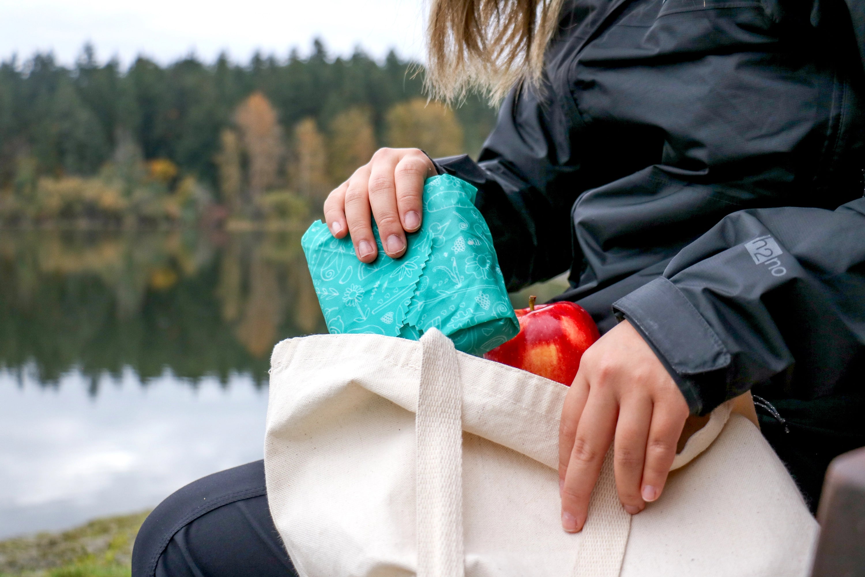 Lush cosmetics beeswax wraps. A teal wrap with custom artwork on the wrap. Image shows this gifted custom beeswax wrap used to take a sandwich on the go. 