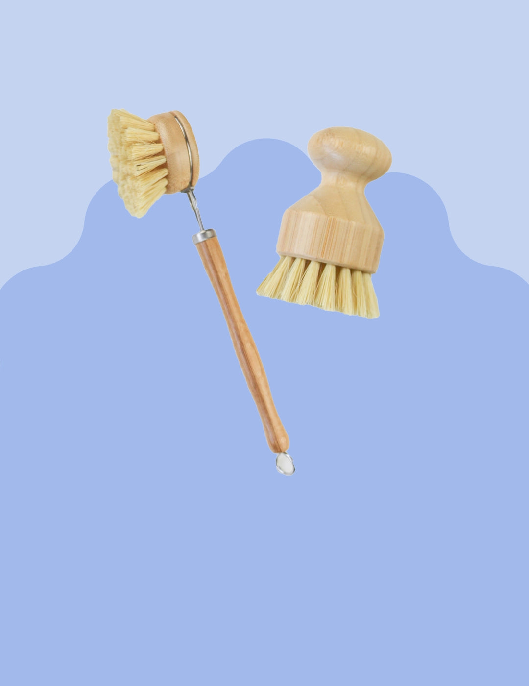 Two durable scrubrushes made fro eco friendly bamboo material being held over top of a sudsy sink. One scrub brush has a long handle and replaceable head and the other is a short scrub brush with ergonomic handle.